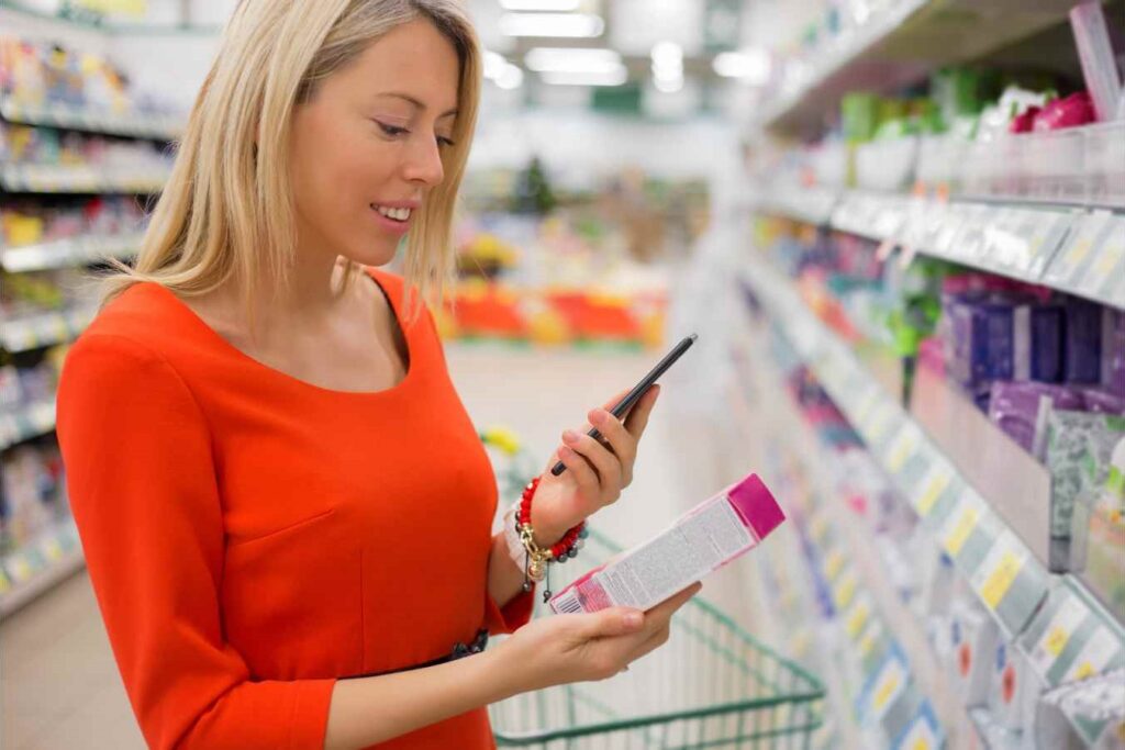 Woman scanning an article in a supermarket with a smartphone and Viziotix retail barcode scanner self scanning software. Also known as Barcode Reader SDK or Barcode Decoder SDK